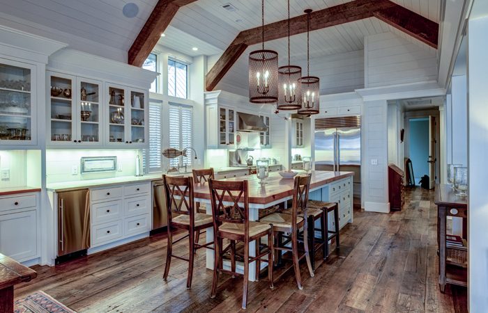 Large expensive chefs kitchen in luxury home with rough hewn wood and white cabinets.